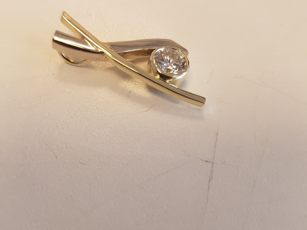Langwerpig sieraad van wit- en geelgoud met een diamant in de zetting