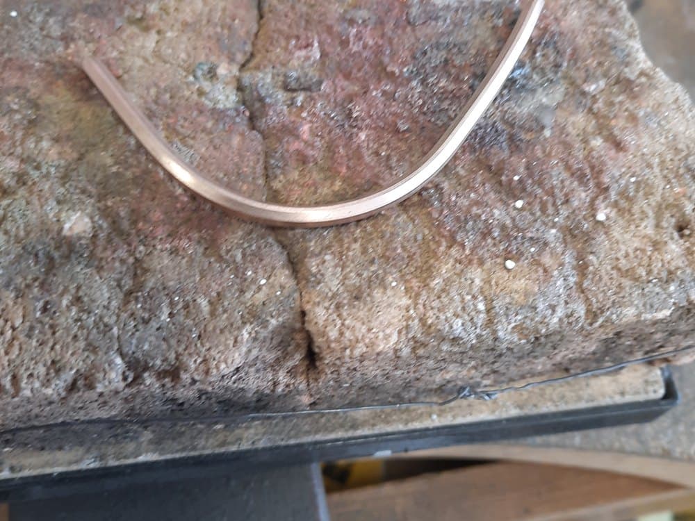 Gebogen staaf roodgoud op de soldeersteen, het begin van een nieuwe ring
