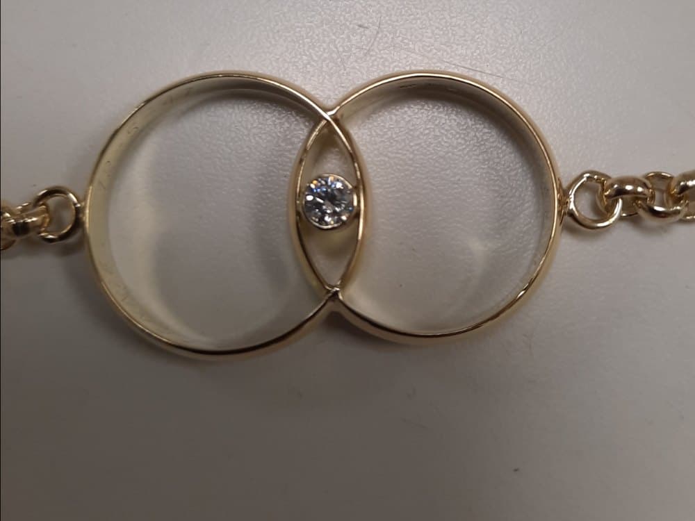 Twee ineengeschoven gouden ringen met een diamant, aan een schakelketting